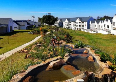 Landscape design with multi-level garden beds, paved walkways, and manicured hedges at a Durban residential complex by Creative Landscapes