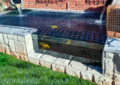 Peaceful koi pond with aquatic plants and stone water features in a Durban garden by Creative Landscapes