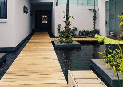 Timber walkway over a tranquil water feature in a landscaped Durban garden by Creative Landscapes
